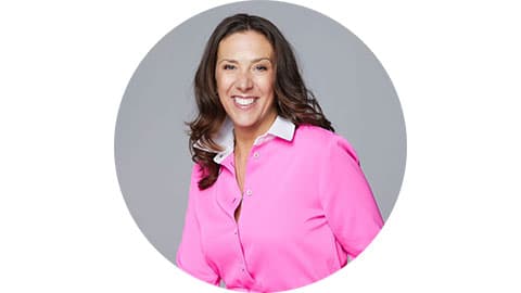 A headshot of Georgie Dickens. She is wearing a pink shirt with a white collar and she is smiling at the camera. The background is white and her image is centred in a grey circle.